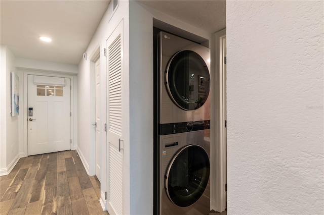 clothes washing area with stacked washer / drying machine and dark hardwood / wood-style floors