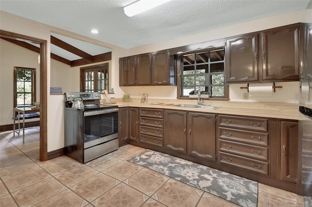 kitchen featuring stainless steel range with electric stovetop, sink, vaulted ceiling with beams, light tile patterned floors, and dark brown cabinetry