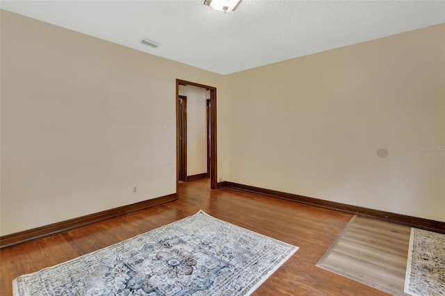 unfurnished room featuring wood-type flooring and a textured ceiling