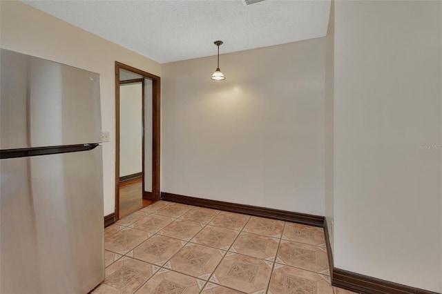 unfurnished dining area with light tile patterned flooring and a textured ceiling