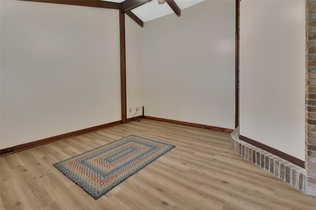 spare room with vaulted ceiling with beams, ceiling fan, and light wood-type flooring