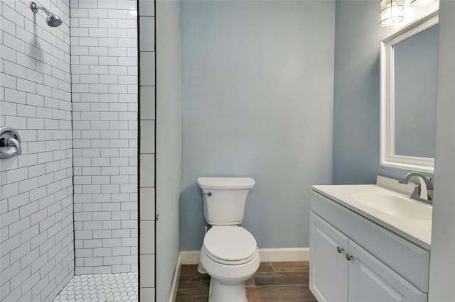 bathroom featuring toilet, a tile shower, and vanity