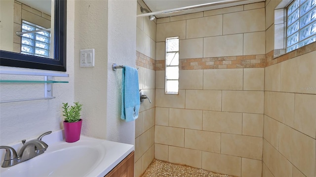 bathroom with tiled shower and sink