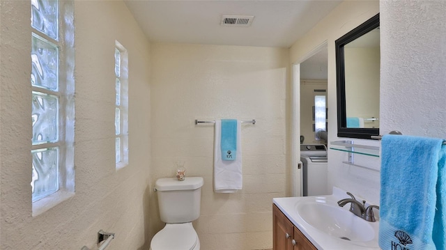 bathroom with washer / clothes dryer, a wealth of natural light, and toilet