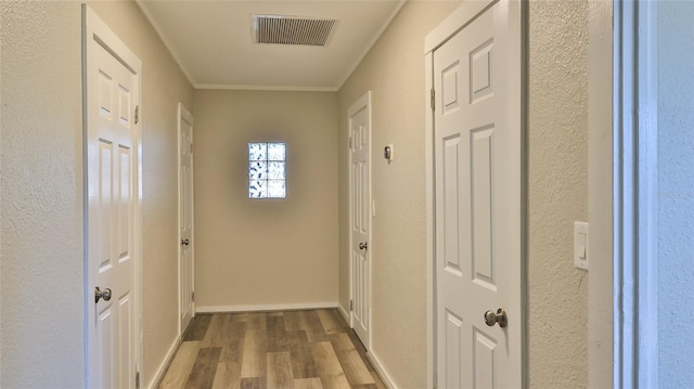 corridor with light hardwood / wood-style floors and ornamental molding