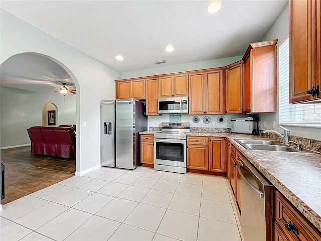 kitchen featuring a wealth of natural light, ceiling fan, sink, stainless steel appliances, and light tile patterned floors