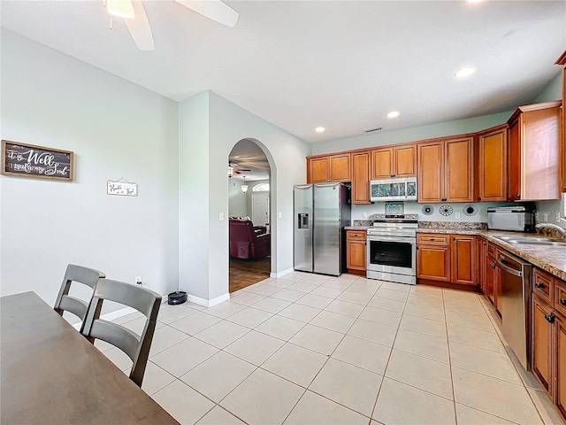 kitchen featuring light tile patterned flooring, appliances with stainless steel finishes, light stone countertops, and sink