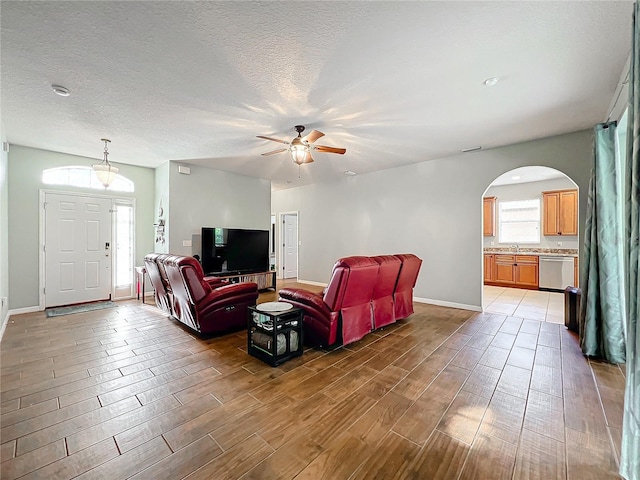 living room featuring ceiling fan, sink, and a textured ceiling