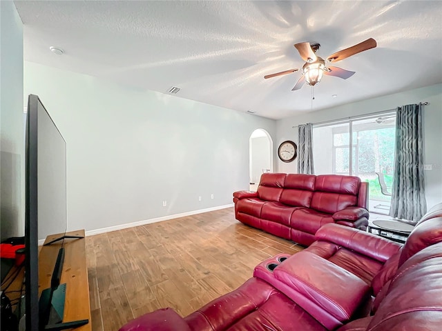 living room with ceiling fan, wood-type flooring, and a textured ceiling