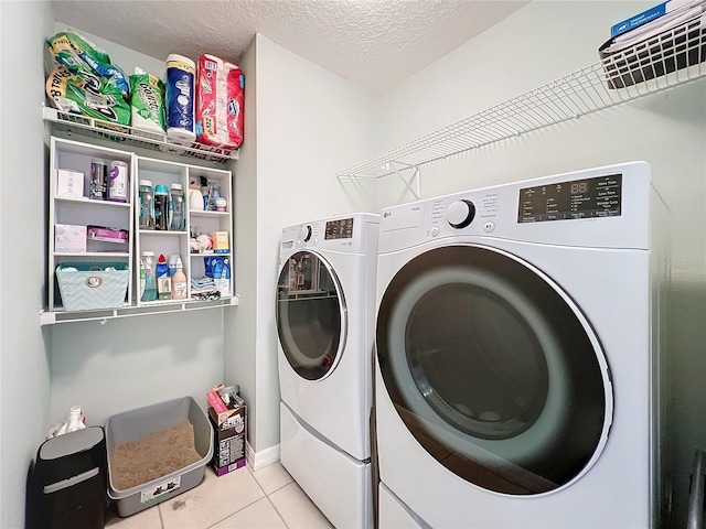 laundry area featuring light tile patterned floors, washer and dryer, and a textured ceiling