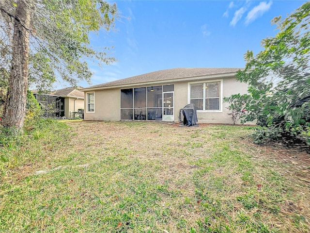 back of property with a sunroom and a lawn