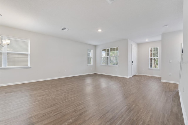 spare room with dark wood-type flooring and a notable chandelier