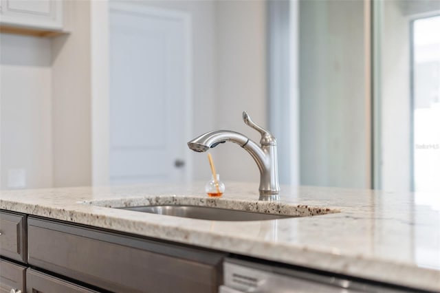 details featuring light stone countertops, sink, white cabinets, and dishwashing machine