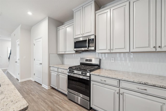 kitchen with light stone countertops, decorative backsplash, and stainless steel appliances