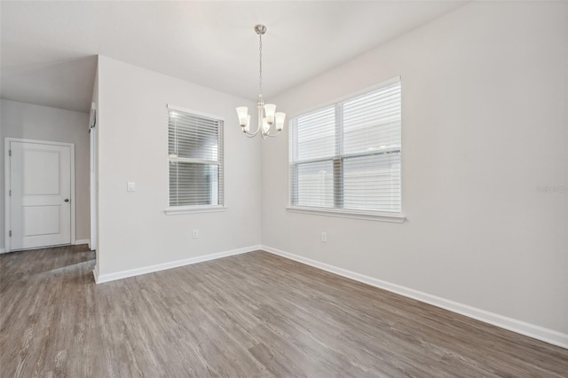 spare room featuring a chandelier and hardwood / wood-style floors