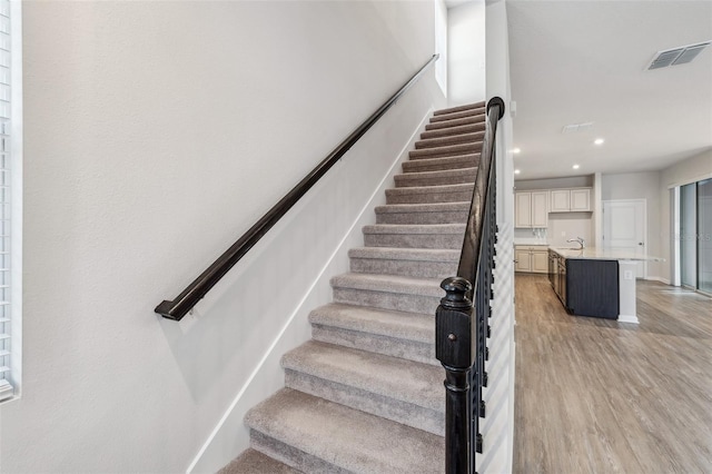 stairs featuring wood-type flooring and sink