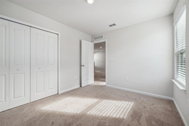 unfurnished bedroom featuring carpet flooring, multiple windows, and a closet