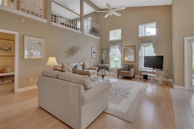 living room with a towering ceiling, light hardwood / wood-style flooring, and ceiling fan