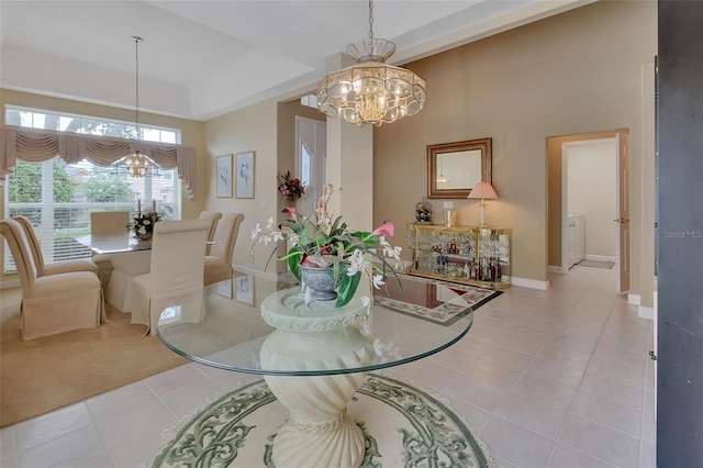 dining area with a tray ceiling, light tile patterned floors, and an inviting chandelier