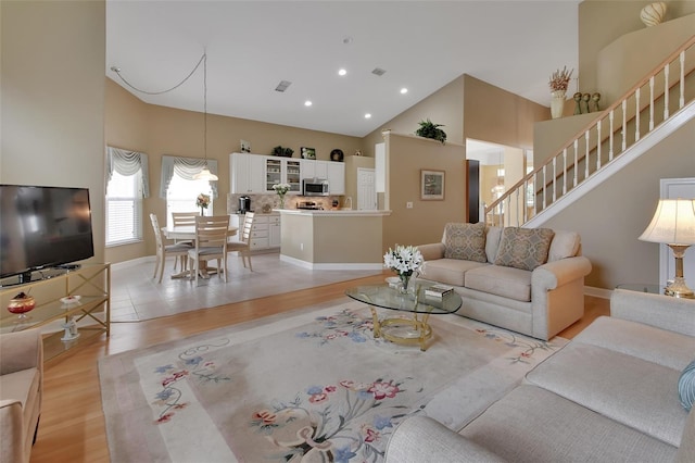 living room with high vaulted ceiling and light wood-type flooring