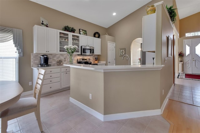 kitchen with white cabinetry, light tile patterned floors, vaulted ceiling, and appliances with stainless steel finishes