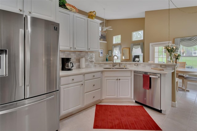 kitchen featuring white cabinetry, kitchen peninsula, decorative light fixtures, decorative backsplash, and appliances with stainless steel finishes