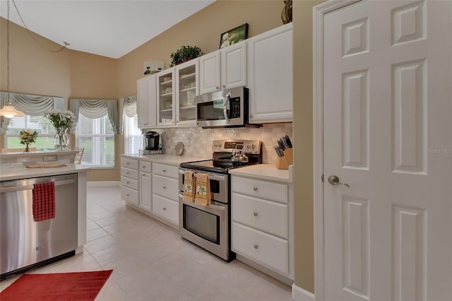 kitchen with white cabinetry, hanging light fixtures, stainless steel appliances, tasteful backsplash, and light tile patterned floors