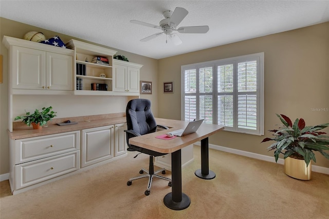 carpeted office featuring a textured ceiling and ceiling fan