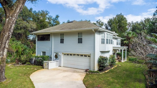 view of front facade with cooling unit, a garage, and a front yard