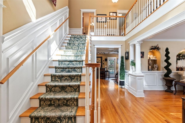 stairs featuring ornate columns, crown molding, and hardwood / wood-style flooring