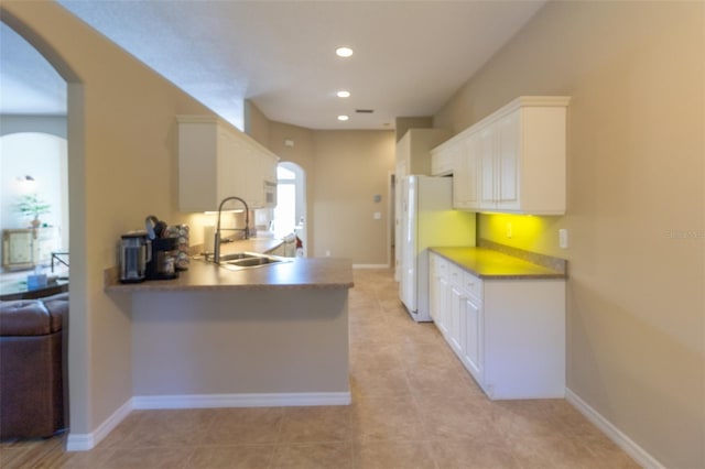 kitchen with kitchen peninsula, white appliances, white cabinetry, and sink