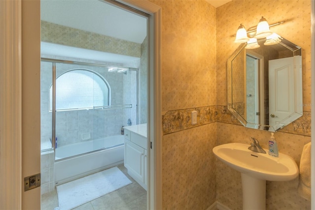 bathroom with combined bath / shower with glass door, tile patterned floors, and sink