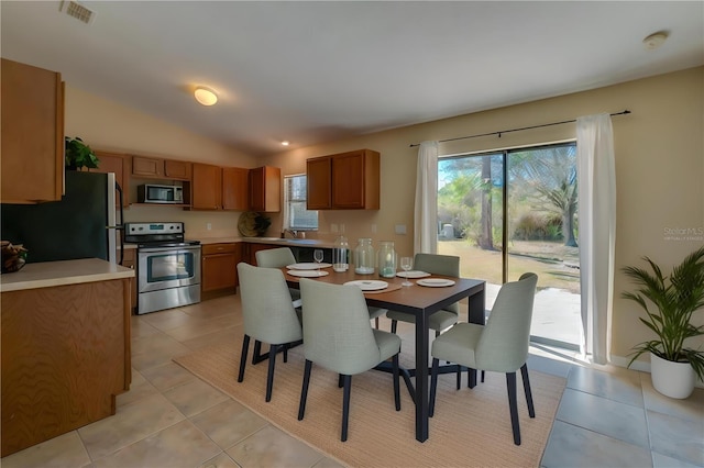 tiled dining area featuring vaulted ceiling, plenty of natural light, and sink