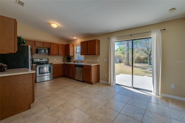 kitchen with sink, light tile patterned floors, lofted ceiling, and appliances with stainless steel finishes