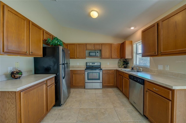 kitchen with light tile patterned flooring, stainless steel appliances, vaulted ceiling, and sink