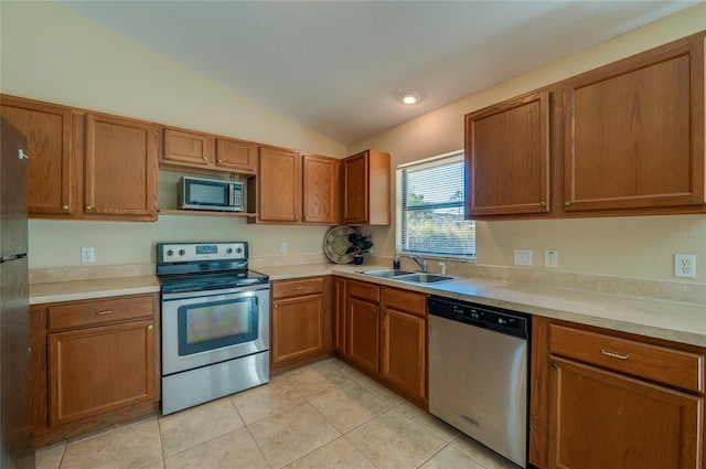 kitchen featuring sink, light tile patterned floors, stainless steel appliances, and lofted ceiling