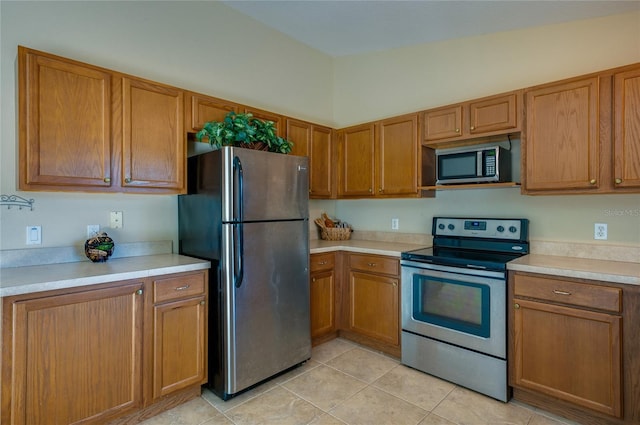 kitchen with light tile patterned flooring, stainless steel appliances, and vaulted ceiling