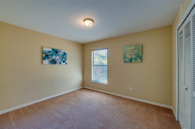 unfurnished bedroom featuring light colored carpet, a textured ceiling, and a closet