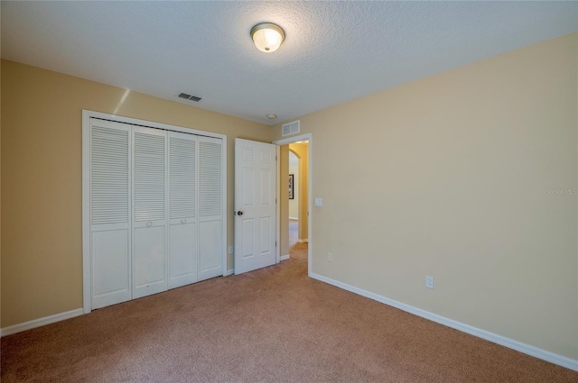 unfurnished bedroom with a closet, carpet floors, and a textured ceiling