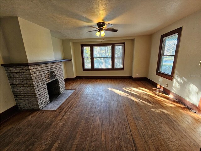 unfurnished living room featuring ceiling fan, dark hardwood / wood-style flooring, a textured ceiling, and a brick fireplace