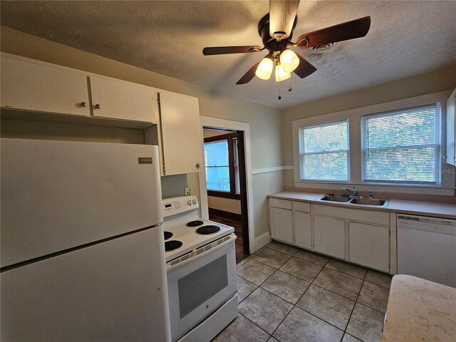 kitchen featuring white appliances, white cabinets, sink, light tile patterned floors, and a textured ceiling