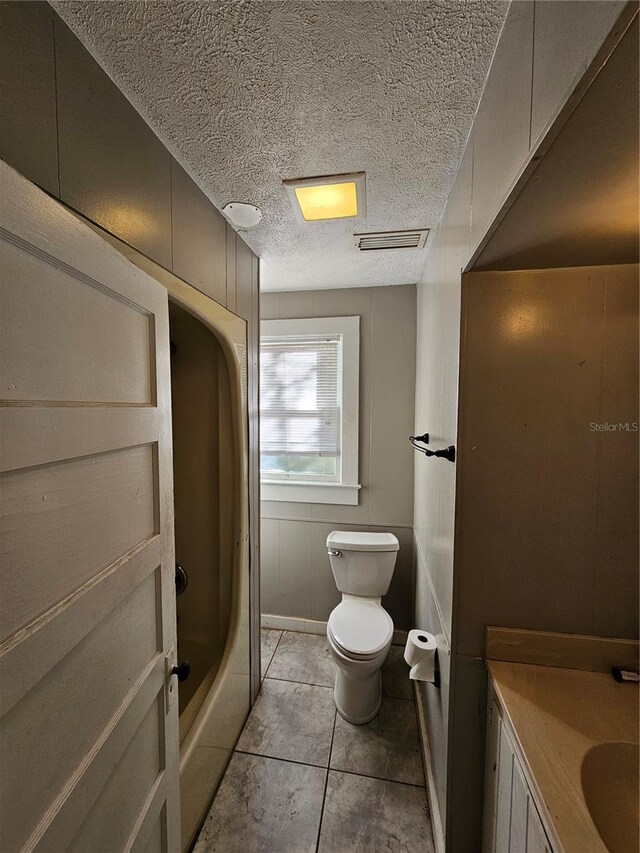 bathroom with tile patterned floors, vanity, toilet, and a washtub