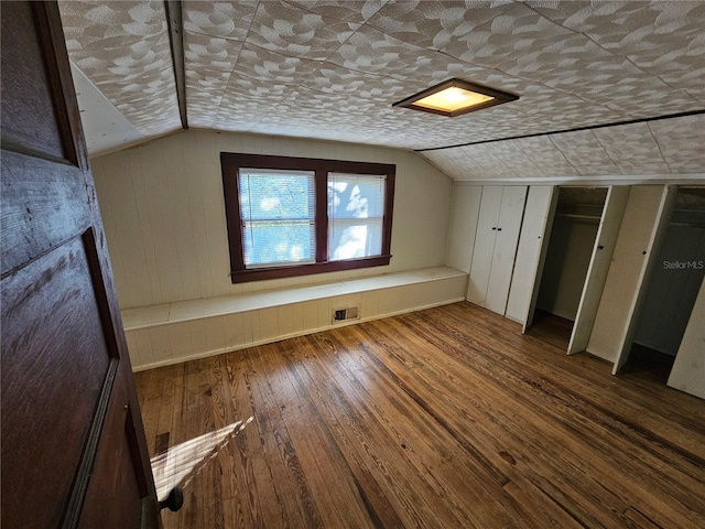 additional living space with hardwood / wood-style floors, wooden walls, and lofted ceiling