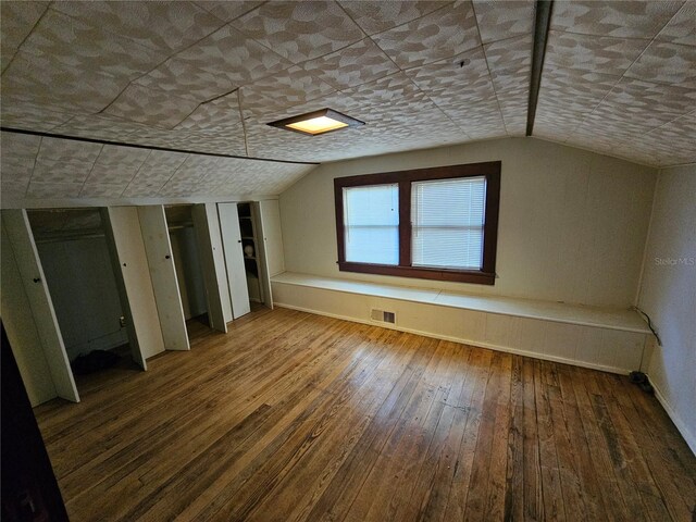 additional living space with wood-type flooring and vaulted ceiling