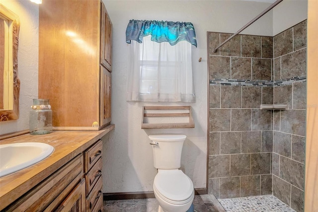 bathroom with vanity, toilet, and tiled shower