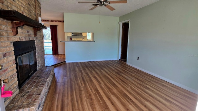 unfurnished living room with ceiling fan, a fireplace, dark wood-type flooring, and a textured ceiling