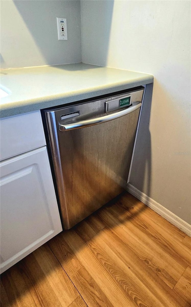 room details with white cabinetry, light hardwood / wood-style flooring, and stainless steel dishwasher