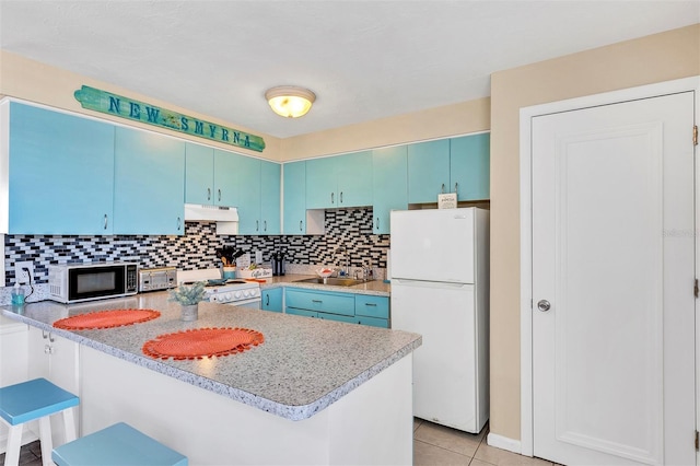 kitchen featuring light tile patterned floors, white appliances, kitchen peninsula, and a breakfast bar area