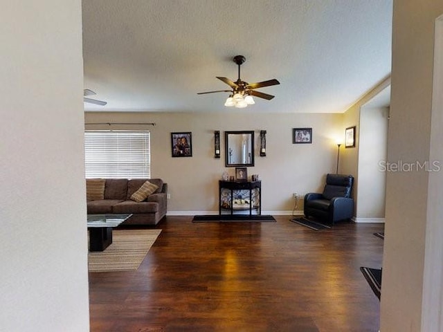 living room featuring ceiling fan, dark hardwood / wood-style flooring, and a textured ceiling