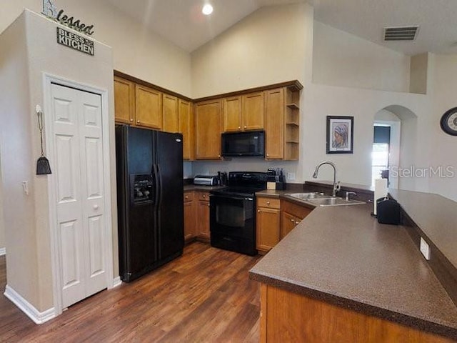 kitchen with dark wood-type flooring, high vaulted ceiling, black appliances, sink, and kitchen peninsula